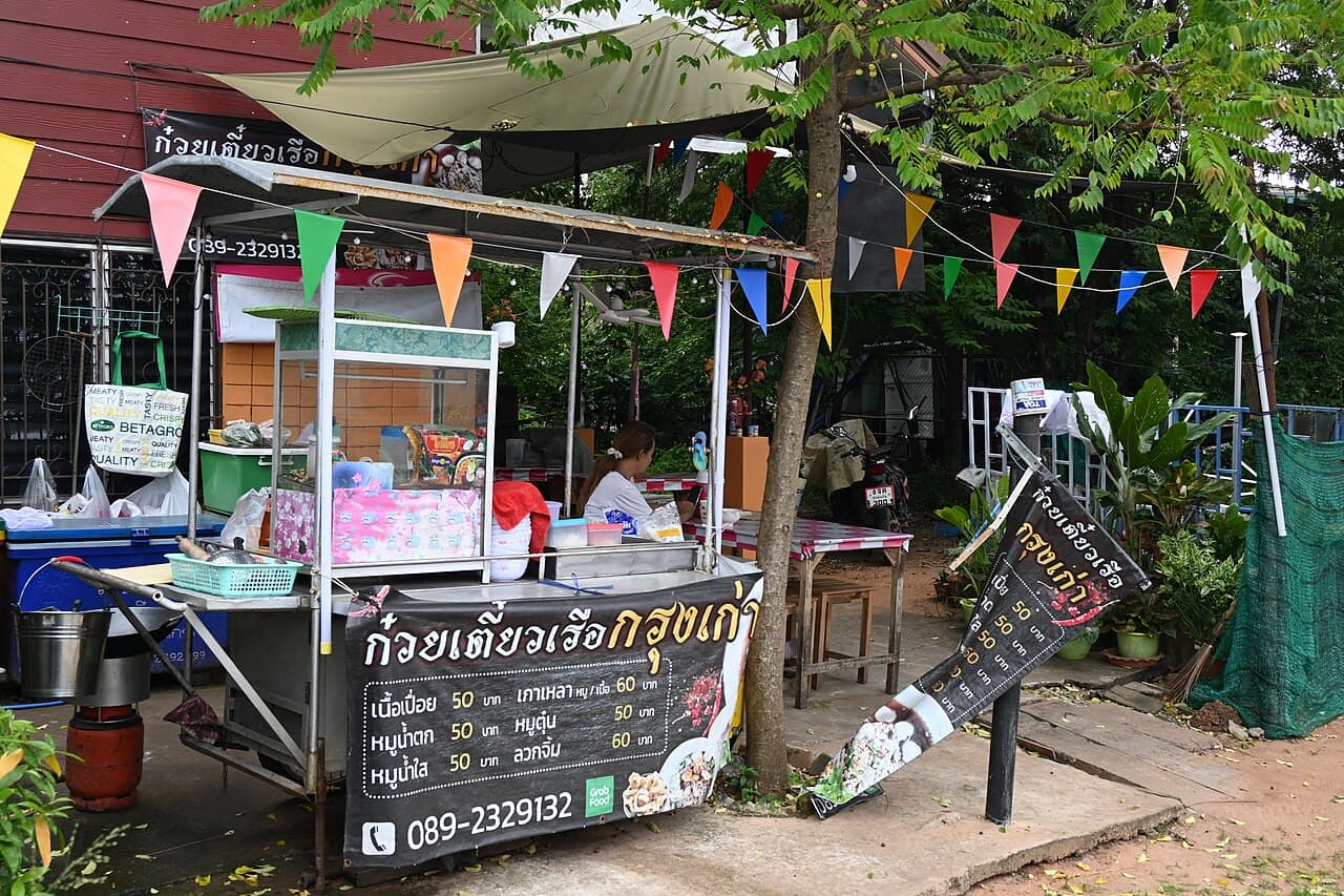 Boat noodle stall menu banner — ก๋วยเตี๋ยวเรือกรุงเก่า with dish names and prices in Thai